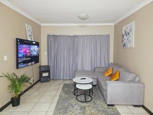a living room with a couch and a tv at Welcome Home in Midrand