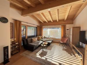 a living room with a black leather couch and a large window at Apartment ZillerSoul in Uderns
