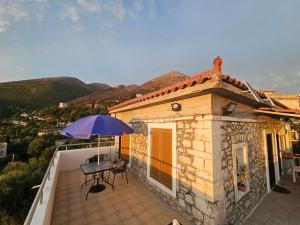a patio with a table and an umbrella on a balcony at Ionian Sunset House in Piqeras
