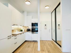 a kitchen with white cabinets and a hardwood floor at Peony Suite Presidential Garden Free Parking in Bratislava +14 photos