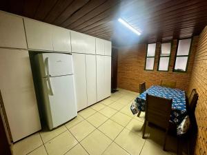 a kitchen with a table and a refrigerator at Suíte king com ar condicionado in Botucatu