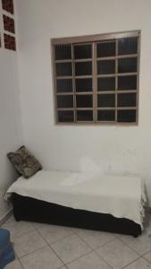a bed in a white room with a window at Quarto Conjugado in Itajubá +2 photos