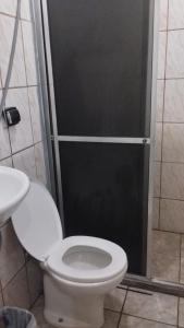 a bathroom with a toilet and a glass shower door at Quarto Conjugado in Itajubá