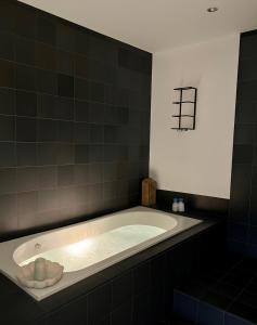a bath tub in a black tiled bathroom at Lowry River Twin Balcony Deluxe in Manchester