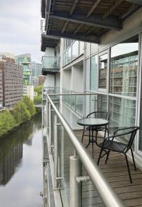 a balcony with a table and chairs next to a river at Lowry River Twin Balcony Deluxe in Manchester