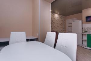 a kitchen with white chairs and a table and a refrigerator at Harkovskaya 37 in Sumy