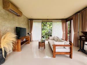 a living room with a couch and a tv at ElForest Villa Ubud, Payangan in Payangan