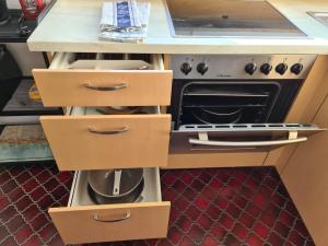 Una cocina con cajones de madera y un horno abierto. en Sunny studio in Grenzach, ideal location to Basel, en Grenzach-Wyhlen