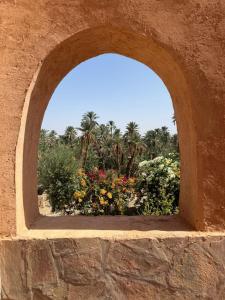 an arch in a stone wall with flowers and palm trees at Auberge et Restaurant chez Alilouch in Nkob