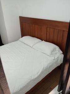 Una cama con sábanas blancas y un cabecero de madera. en Villa Candelaria Hostel, en Bogotá