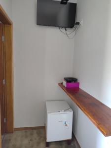 a room with a shelf and a television on a wall at Chalésforquilha in Delfinópolis