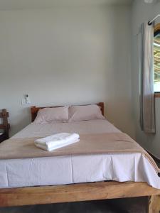 a bed with a white towel on top of it at Chalésforquilha in Delfinópolis +12 photos