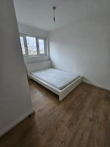 Una habitación blanca con una cama y una ventana. en Spacious room, en Londres