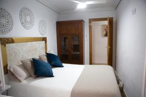 a bedroom with a large white bed with blue pillows at Apartamento El Oso y el Madroño II Thematic in Villena