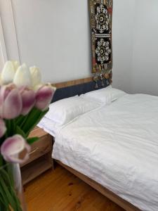 two beds in a room with a vase of flowers at Alay-Art Hotel in Osh +3 photos