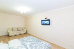 Una habitación con una cama y un sofá y un televisor en la pared. en Apart-Hotel, en Sumy