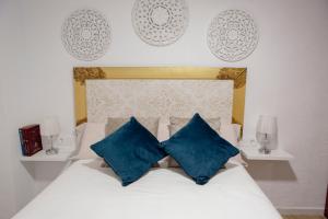 a bedroom with a white bed with blue pillows at Apartamento El Oso y el Madroño II Thematic in Villena