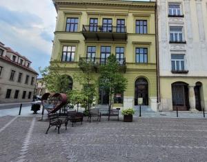 a yellow building with benches in front of it at K2 Apartment in Tarnów