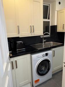 a kitchen with a washing machine and a sink at Jerryinn Rooms in London