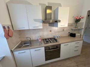 a kitchen with white cabinets and a stove and a sink at Viale Apartment in Isola del Liri