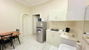 Una pequeña cocina con una mesa y un refrigerador. en مثوى, en Medina