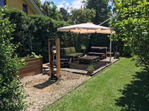 a patio with an umbrella and chairs and a table at Wunderschöne, große Gartenwohnung mit 3 Schlafzimmern Nähe Kaufbeuren in Untergermaringen