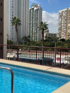 a swimming pool with palm trees and buildings at Alma de Mar in Finestrat