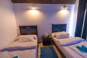 two beds in a room with blue walls at Nubian Spirit in Aswân Reservoir Colony