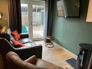 a living room with two leather chairs and a television at Beach hut seaside cottage in Sheringham