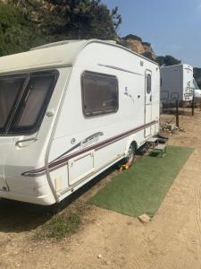 a white rv parked in a field next to some trees at Little hideaway in Costa da Caparica