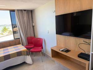 a hotel room with a bed and a flat screen tv at Atlântico Flat - Praia de Ponta Negra - Natal in Natal