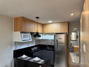 a kitchen with a stainless steel refrigerator and a table at Atlântico Flat - Praia de Ponta Negra - Natal in Natal