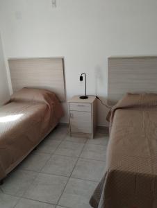 a bedroom with two beds and a lamp on a night stand at Casa de 2 dormitorios in Las Varillas