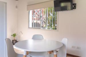 a white table and chairs in a room with a window at Tangerina Apart Hotel - Villa Gesell in Villa Gesell