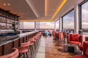 a bar with red chairs and tables and windows at voco Gosford by IHG in Gosford