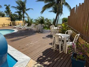 a deck with white tables and chairs next to a pool at Atlântico Flat - Praia de Ponta Negra - Natal in Natal