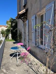 ein Tisch und Stühle vor einem Gebäude in der Unterkunft Meublé Voltour dans la Villa Denise in Vals-les-Bains + 26 Fotos