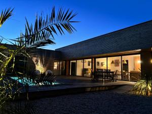 a modern house with a wooden deck at night at 6-person villa with pool in La Celle-sous-Gouzon