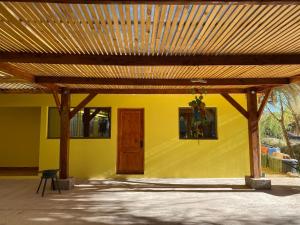 a yellow building with a wooden roof and a door at Inti Wasi habitaciones in San Pedro de Atacama