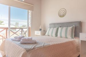 a white bedroom with a bed with towels on it at Tangerina Apart Hotel - Villa Gesell in Villa Gesell +78 photos