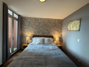 Un dormitorio con una cama y una pared de ladrillo. en Escazu Guachipelin Peaceful Getaway, Pool, Wi-Fi & Work Space CR MARIPOSA RENTALS, en San Rafael