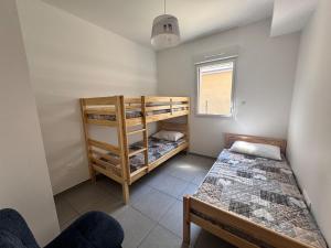 ein Schlafzimmer mit zwei Etagenbetten und einem Fenster in der Unterkunft Appartement neuf T3 avec jardin au bord du lac in Génos
