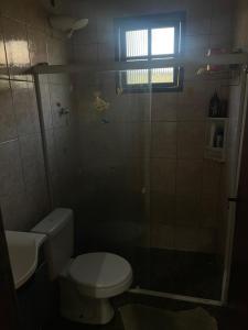 a bathroom with a toilet and a glass shower at Via sol casa 2 térreo in Rio das Ostras
