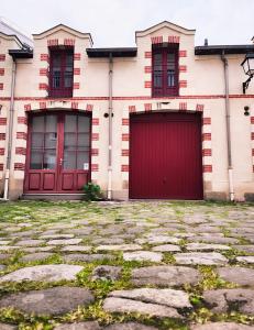 a building with two red doors and a stone driveway at Le Mercœur, appartement calme en hypercentre in Nantes