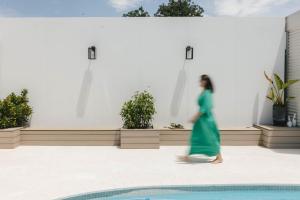 a woman in a green dress walking by a pool at Lynwood Luxe Mudgee in Mudgee