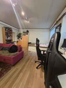 Una sala de estar con un sofá, una silla y un escritorio. en Big and cozy room in the middle of the city, en Trondheim