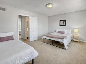 a white bedroom with two beds and a lamp at Gorgeous Clive Charmer, Near Shops, Trails & More! in Clive