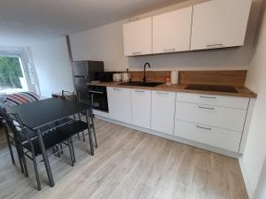 una cocina con armarios blancos, mesa negra y sillas en Studio Saint Marc sur Mer, en Saint-Nazaire