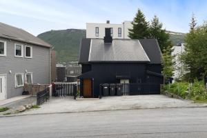 a black house with a fence next to a house at Cozy and spacious apartment in city centre in Tromsø