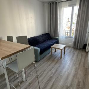 Una sala de estar con un sofá azul y una mesa. en Azal france, en Vanves